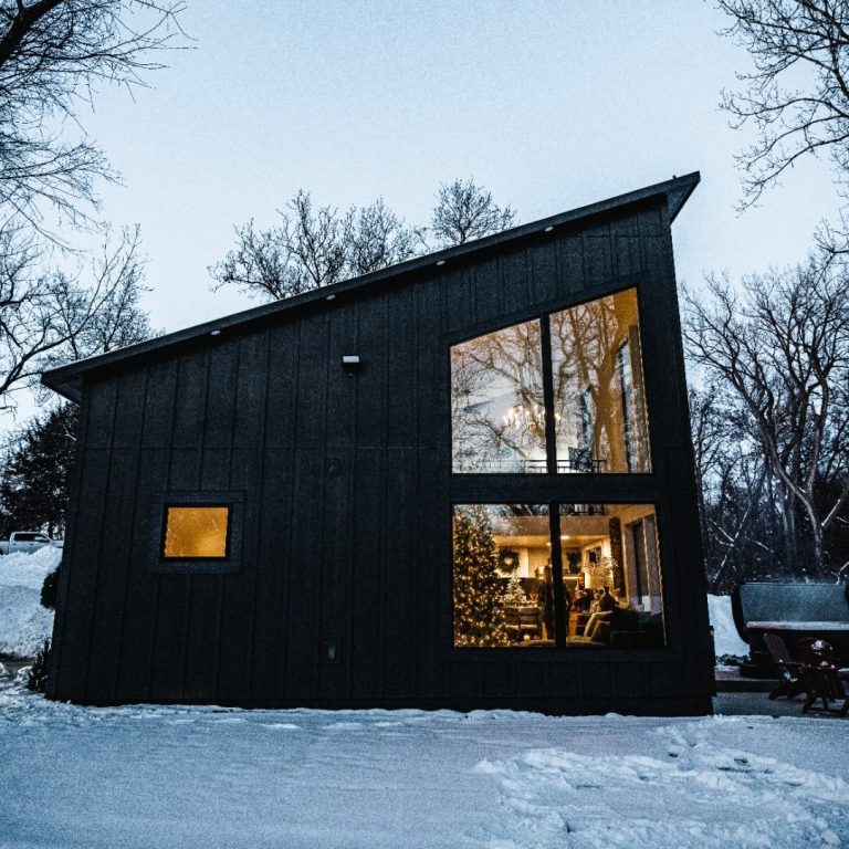 Modern black barn-style venue illuminated at dusk in winter snow