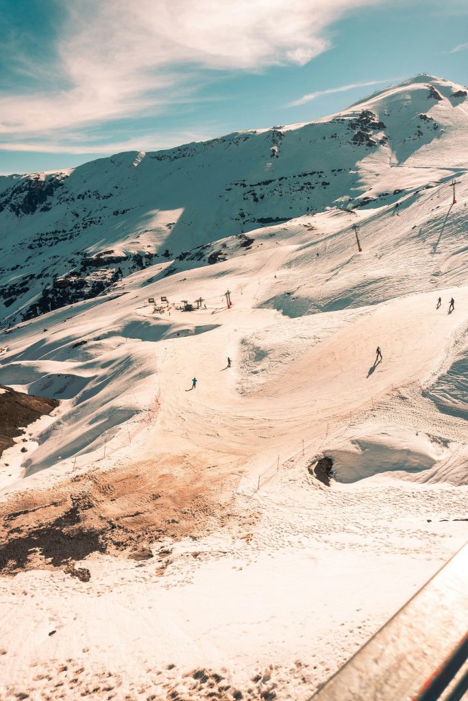 Snow-covered mountain slopes with skiers visible in the distance