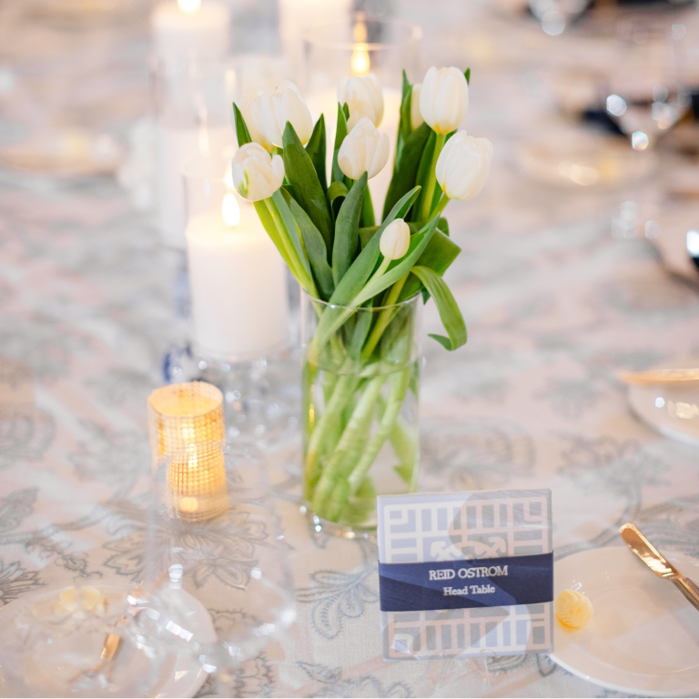 White tulip centerpiece in clear vase with candles and personalized table marker