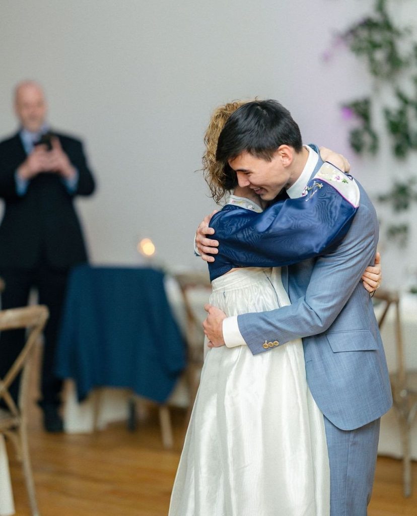 Bride and groom embrace during their reception, both wearing blue attire