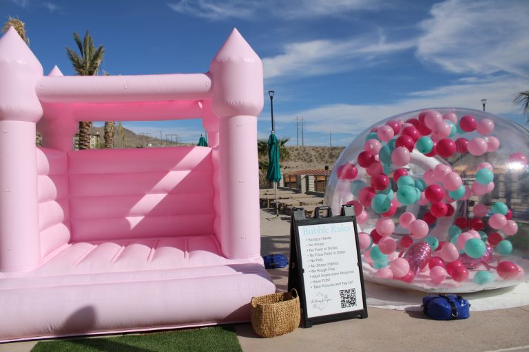 Pink castle bounce house and circular balloon installation at outdoor event venue
