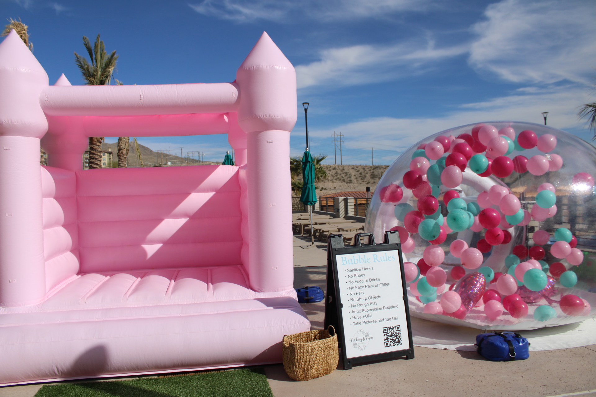Pink castle bounce house and circular balloon installation at outdoor event venue