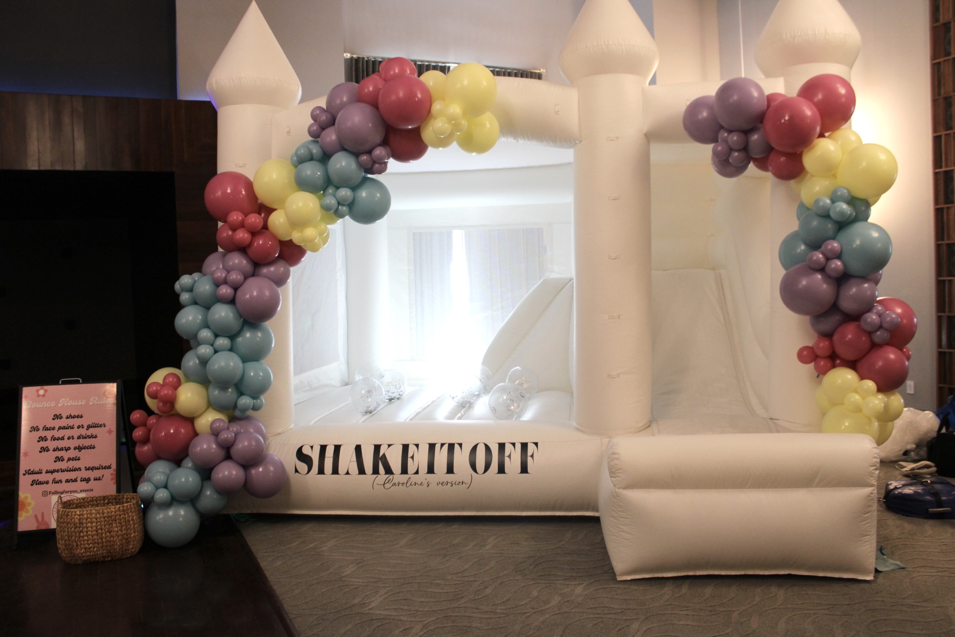 White bounce house with colorful balloon arch and "Shake It Off" event backdrop