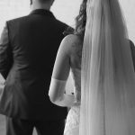 Bride and groom walk together, bride's long veil flowing behind them
