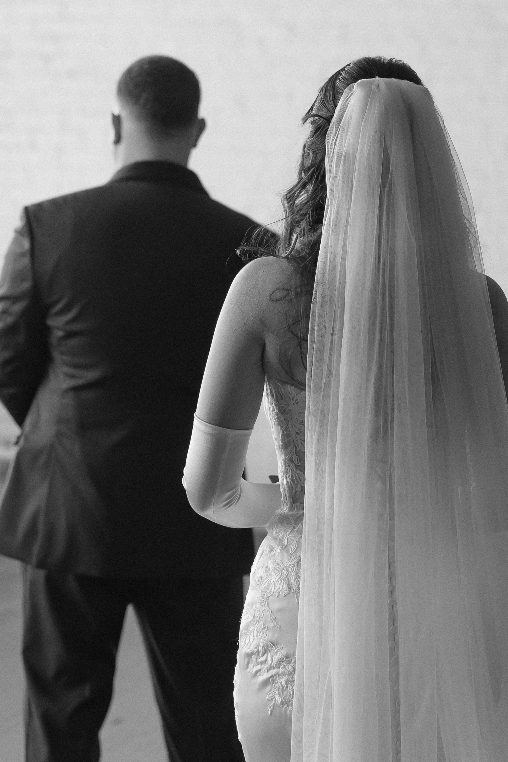Bride and groom walk together, bride's long veil flowing behind them