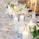 Wedding reception tablescape with white floral centerpieces, blue chinoiserie vases, and glowing candles