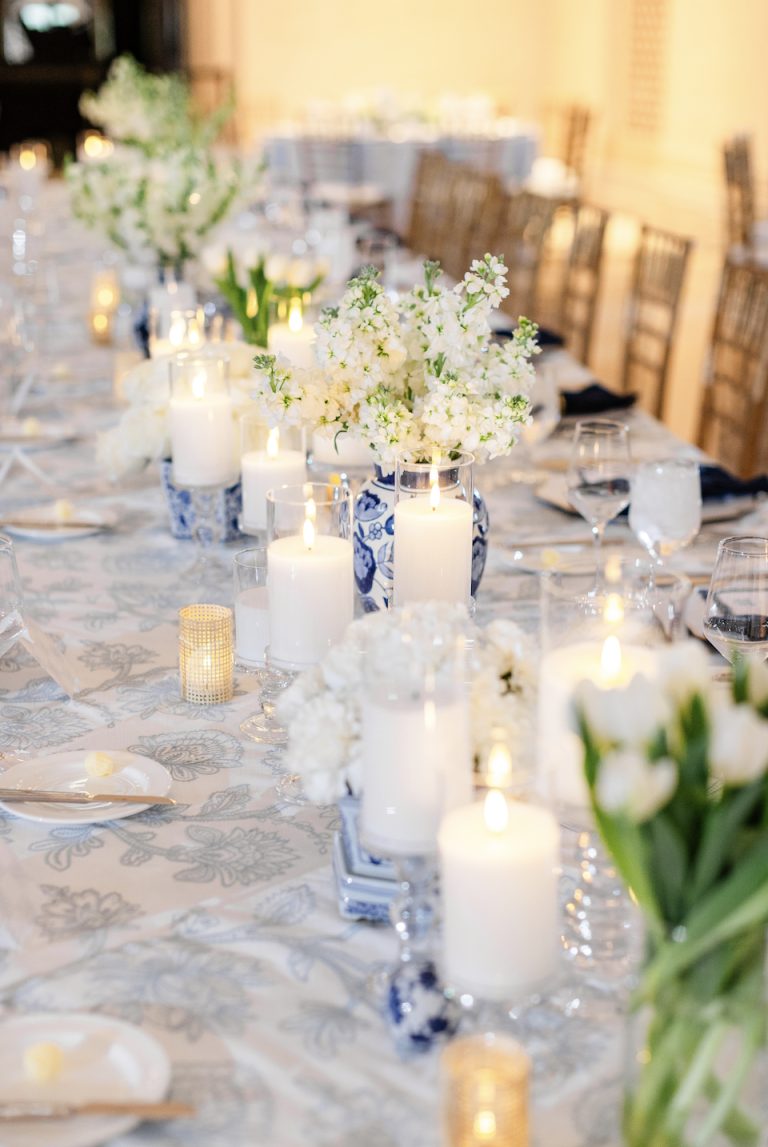 Wedding reception tablescape with white floral centerpieces, blue chinoiserie vases, and glowing candles