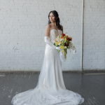 Bride in strapless lace gown with cathedral train holding vibrant yellow, orange, and burgundy cascading bouquet