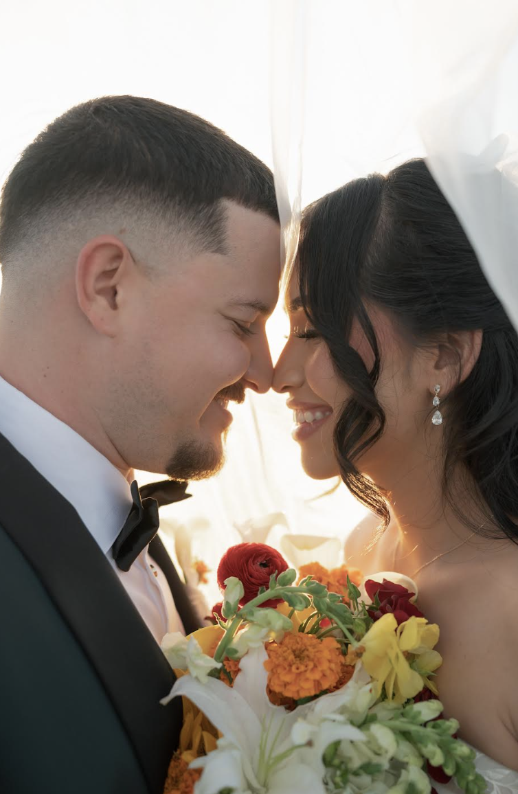 Couple shares intimate moment at sunset with colorful bridal bouquet