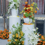 Modern white cake setup featuring white and orange floral decorations on multiple levels
