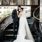 Close-up of newlyweds kissing on grand staircase with flowing bridal veil