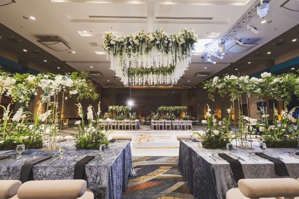 Elegant wedding venue showroom with lush greenery installations, chandelier lighting, and styled seating areas