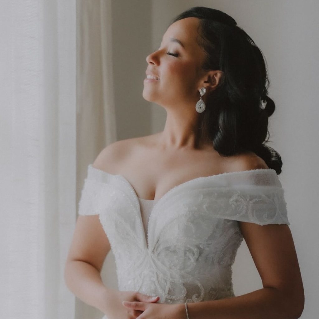 Bride in off-shoulder lace wedding gown with elegant updo and chandelier earrings