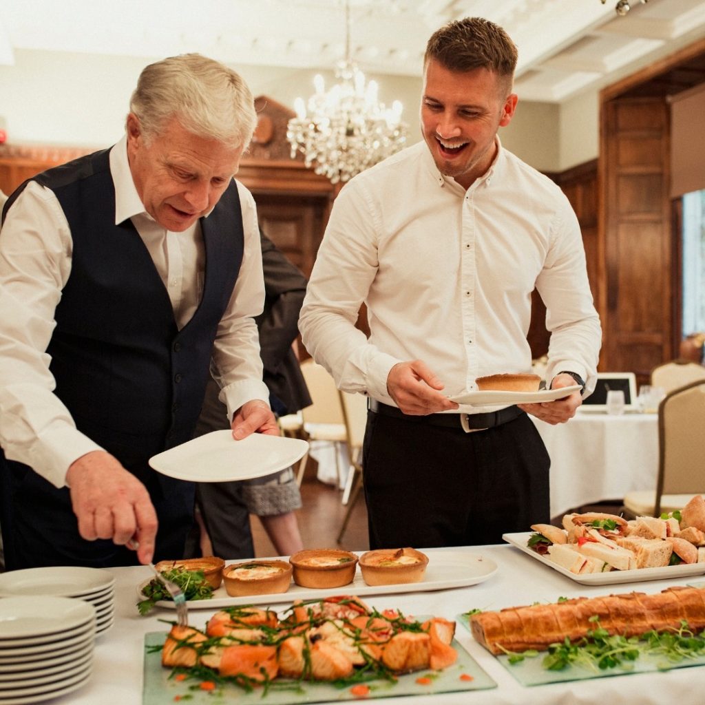 Catering staff serving wedding reception buffet with elegant plated appetizers
