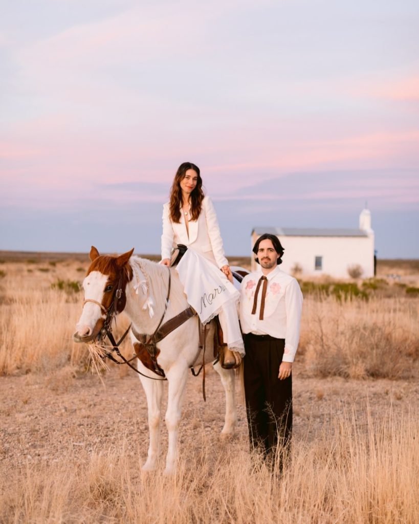 Bride and groom on horseback in open field