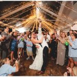 Wedding guests dancing under string lights at outdoor reception venue