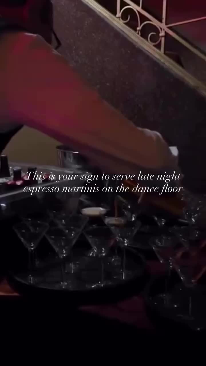 Hand pouring espresso martinis from shaker into cocktail glasses arranged on decorative tray