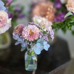 Wedding bouquet featuring dahlias, purple statice, and eucalyptus in clear glass bottle