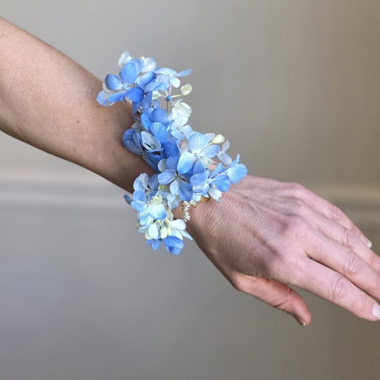 Blue hydrangea wrist corsage worn on outstretched hand