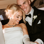 bride and groom in getaway car smiling, bride has white sik gloves and a strapless dress