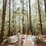 groom spinning his bride with tall trees in the background