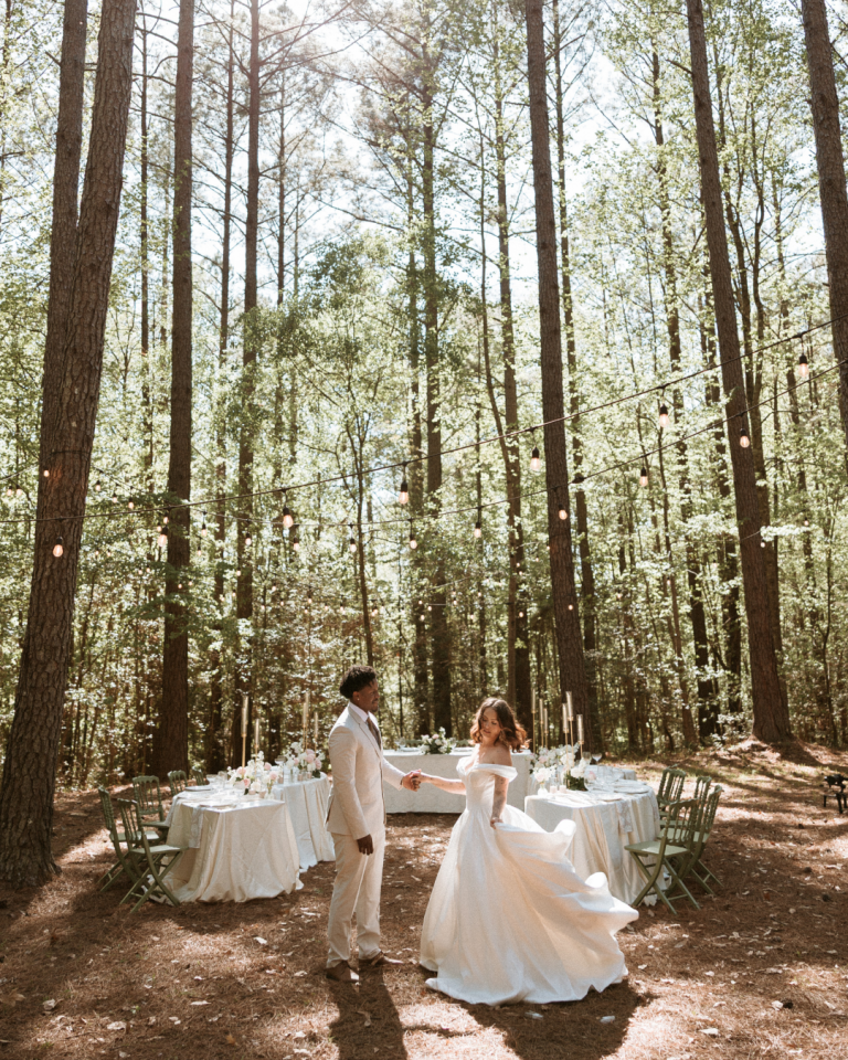 groom spinning his bride with tall trees in the background