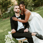 groom sitting in chair and bride standing over him in an editorial pose