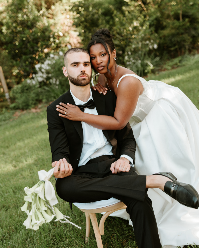 groom sitting in chair and bride standing over him in an editorial pose