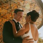 Bride and groom share an intimate moment outdoors with golden sunlight in the background