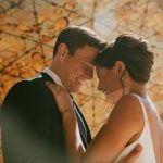 Bride and groom share an intimate moment outdoors with golden sunlight in the background