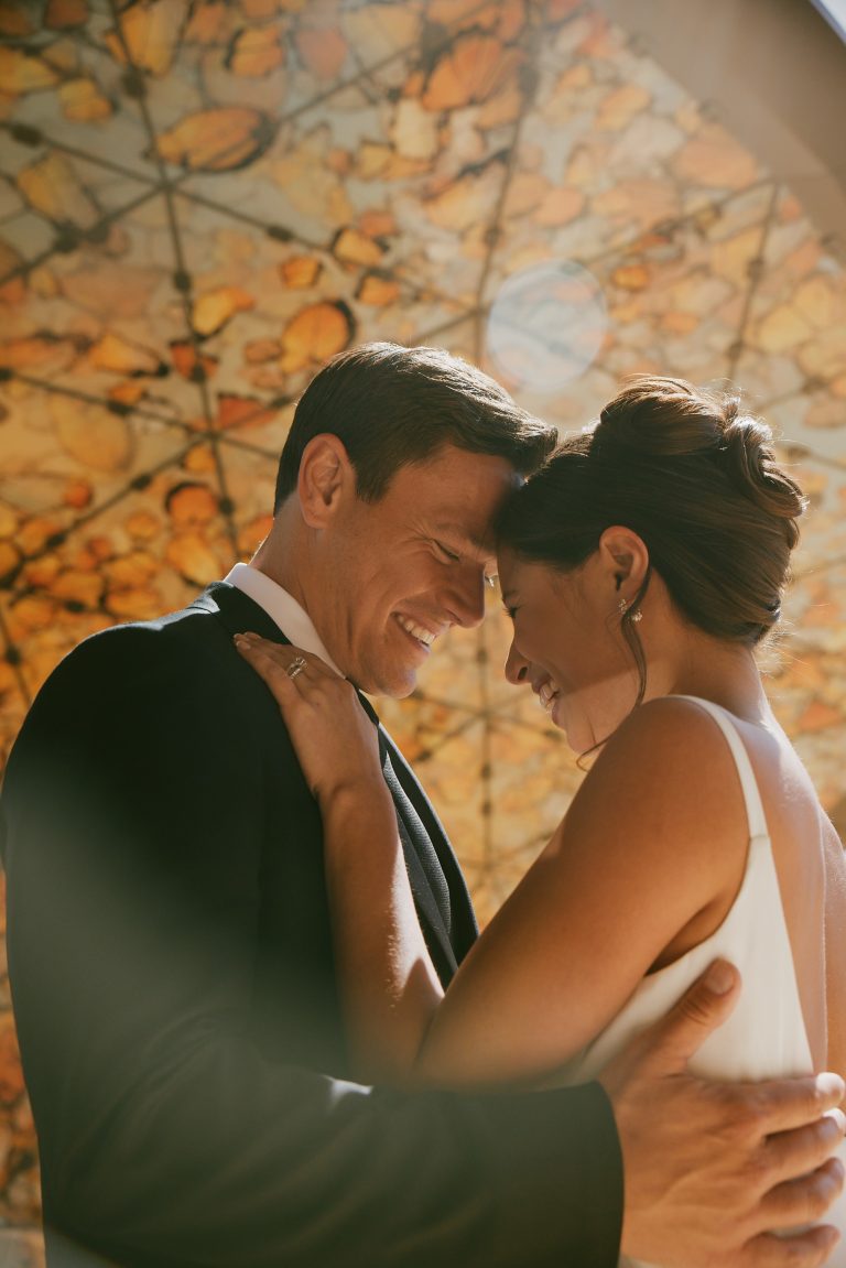 Bride and groom share an intimate moment outdoors with golden sunlight in the background