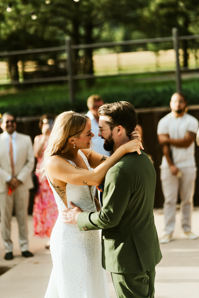 Mallory and Andrew share their first dance on outdoor patio surrounded by guests in white and colorful attire