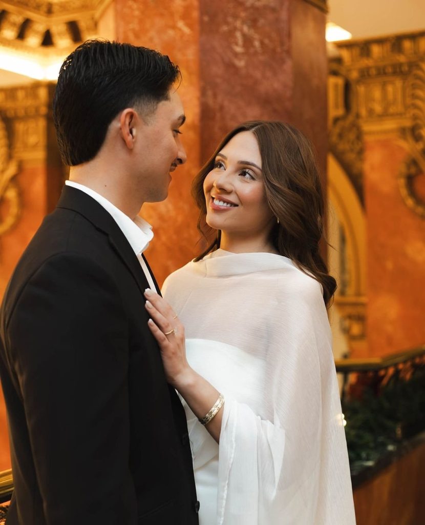 Bride in modern white cape-style dress gazes at groom in Hotel Paso del Norte's grand lobby