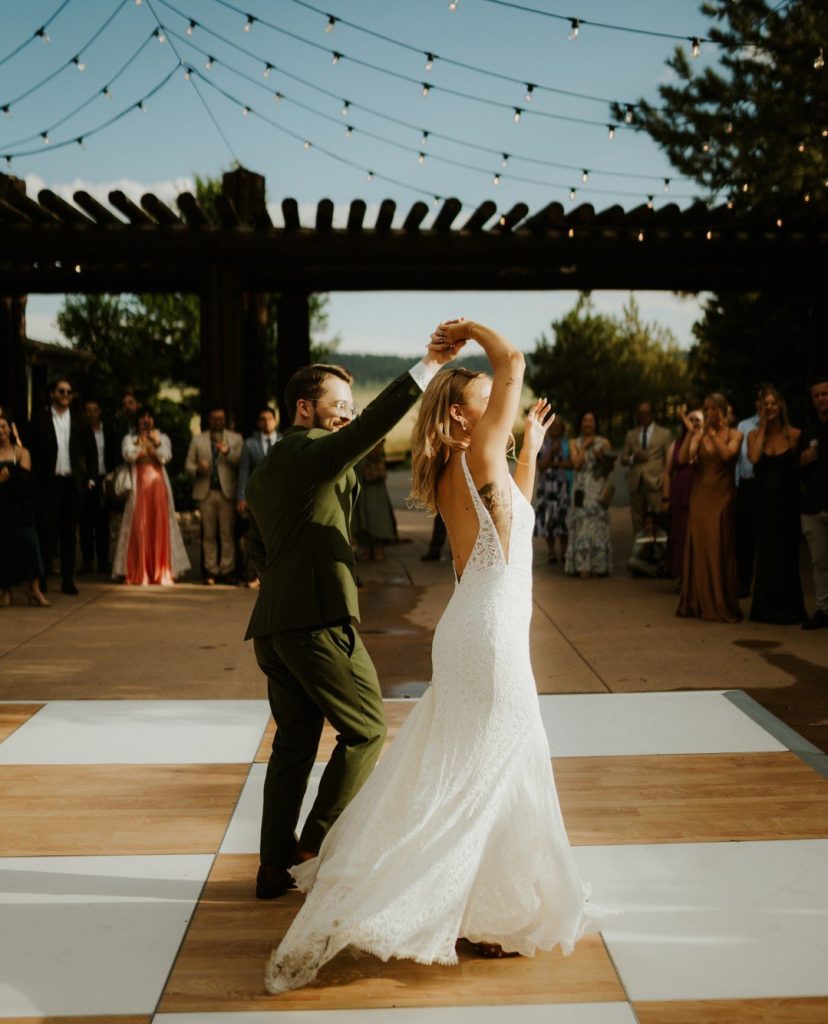 Mallory and Andrew share their first dance on a checkered dance floor under string lights at Spruce Mountain Ranch