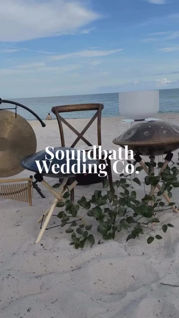 Beachside ceremony setup with sound healing instruments and greenery on sand