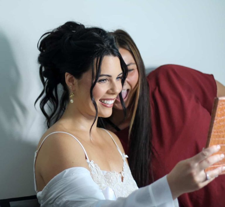 Bride in white lace wedding dress with elegant updo hairstyle smiling during getting ready preparations
