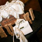 Wooden favor boxes with personalized tags tied with ribbon alongside white flowers
