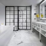 Modern luxury bathroom with black-framed glass shower, white marble, and freestanding tub