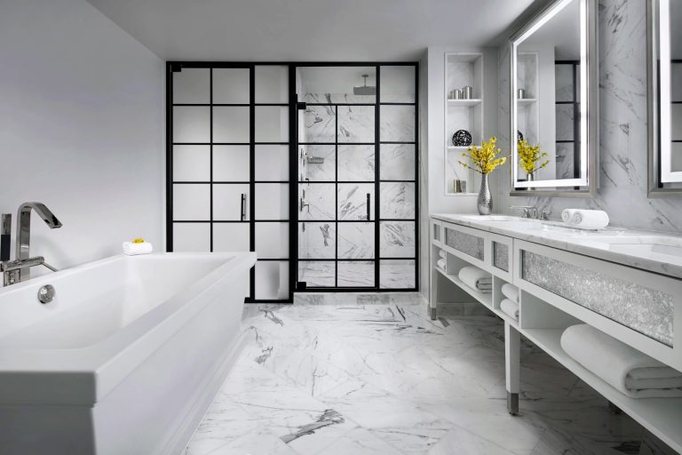 Modern luxury bathroom with black-framed glass shower, white marble, and freestanding tub