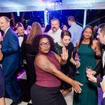 Diverse group of wedding guests dancing and celebrating together at reception