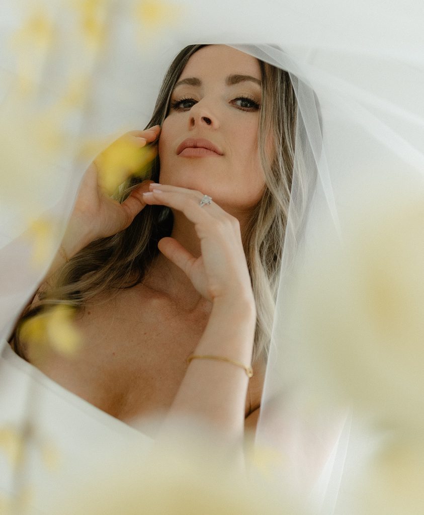 Close-up of bride with natural wedding makeup featuring defined eyes and nude lips, wearing veil