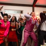 Wedding guests dancing enthusiastically with raised arms at reception