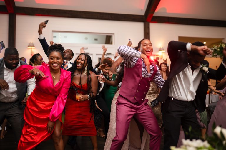 Wedding guests dancing enthusiastically with raised arms at reception