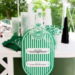 Green and white striped custom bar sign with personalized drink menu under white tent