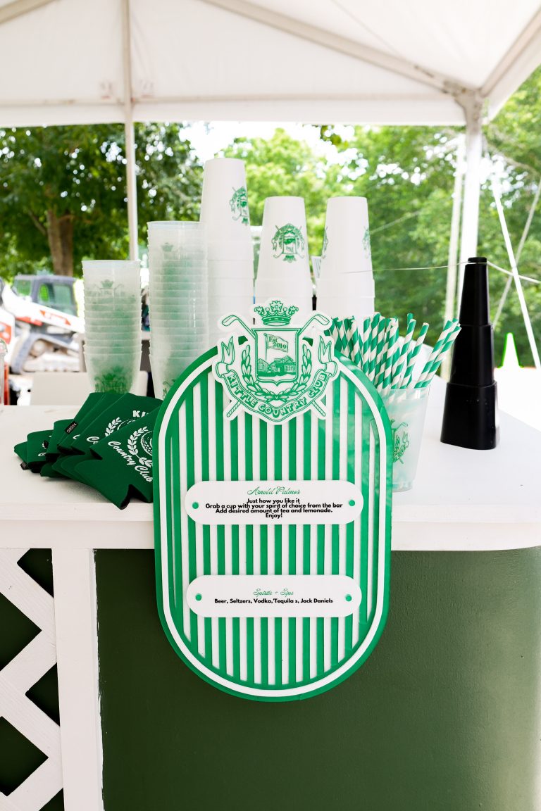 Green and white striped custom bar sign with personalized drink menu under white tent