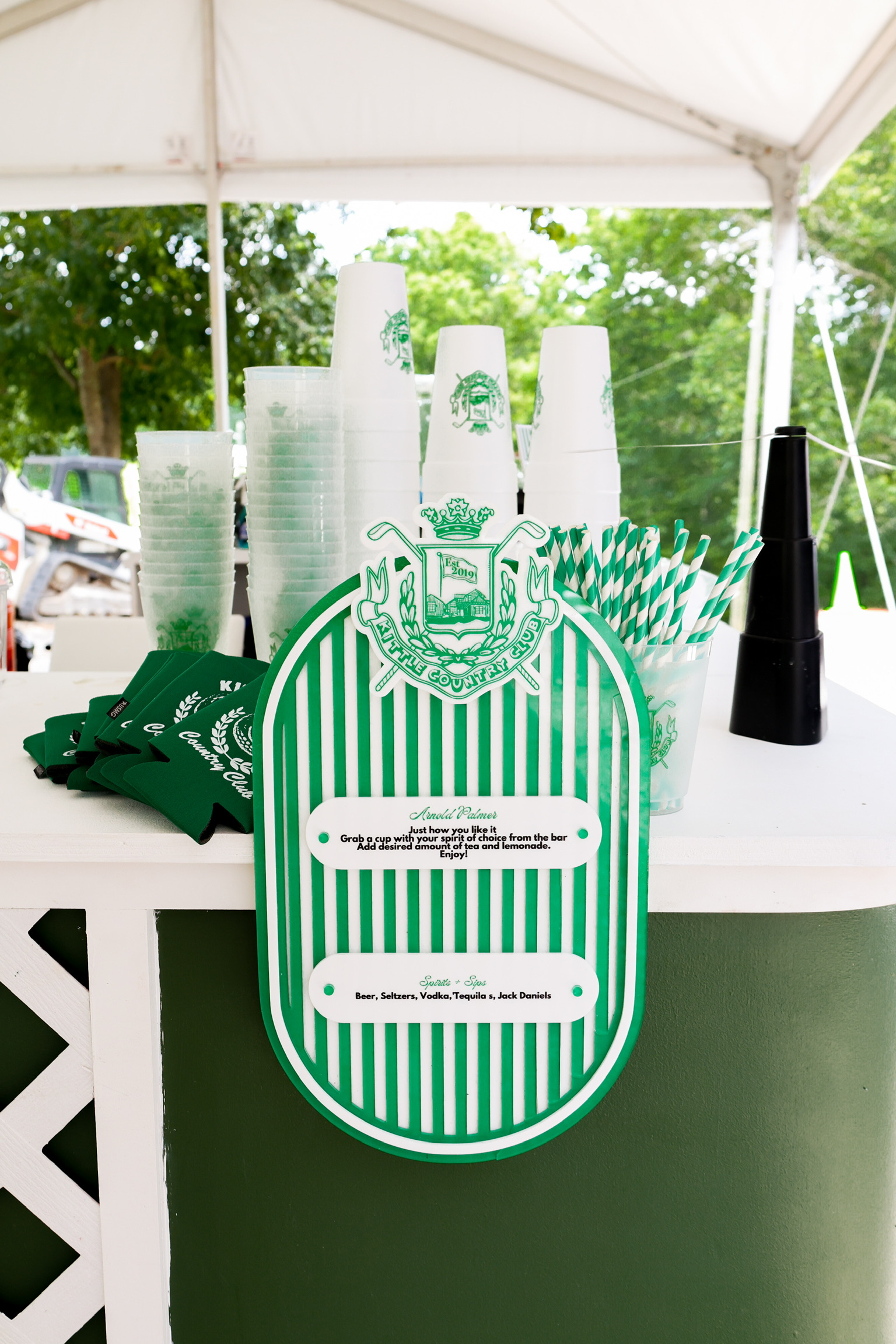 Green and white striped custom bar sign with personalized drink menu under white tent