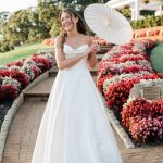 Bride in white ballgown holding bouquet among colorful mum displays at outdoor venue