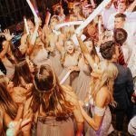 Wedding guests dancing energetically with sparklers on crowded reception dance floor