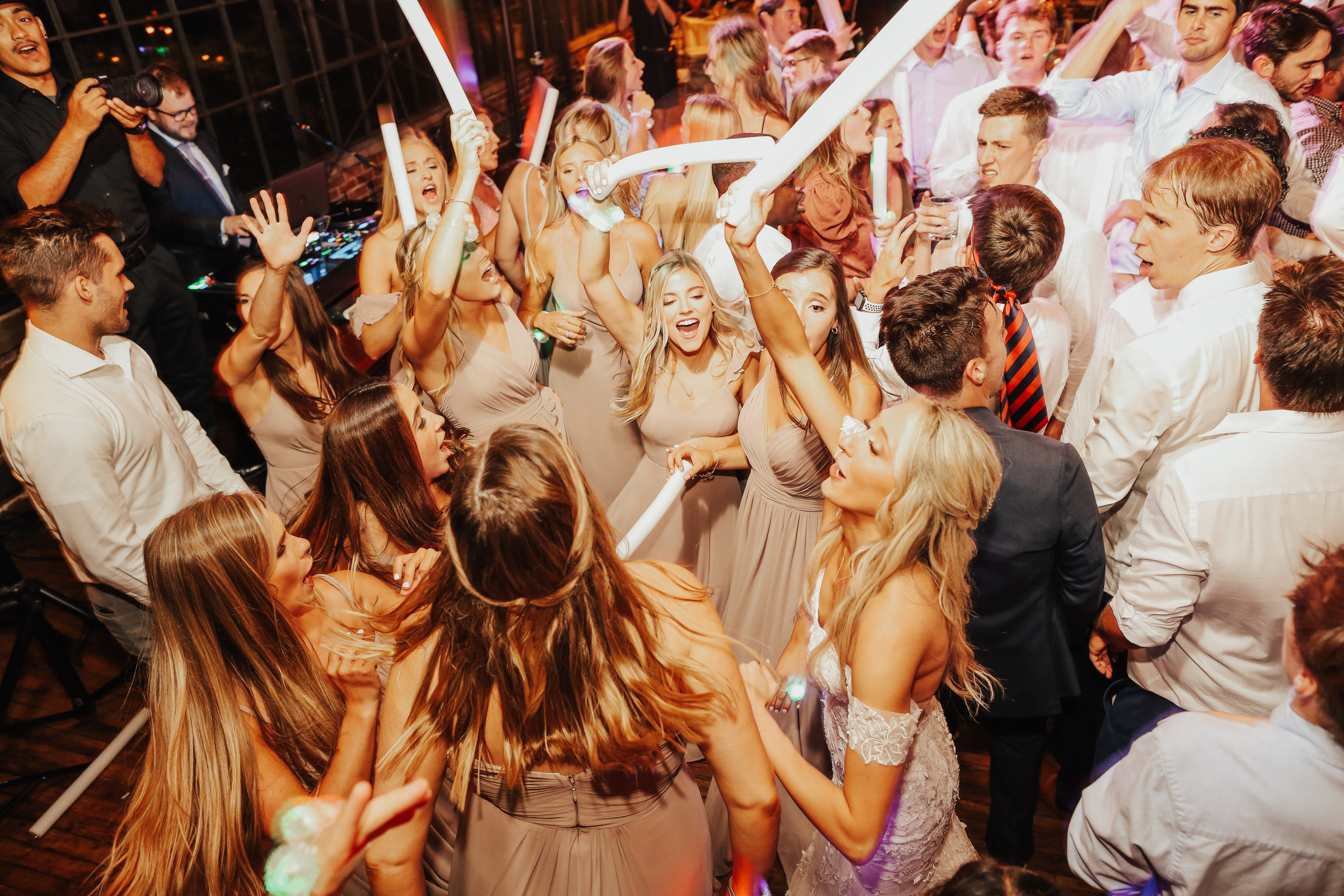 Wedding guests dancing energetically with sparklers on crowded reception dance floor