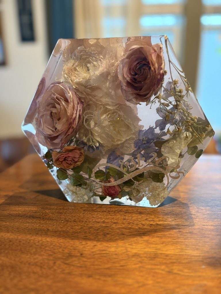 Hexagonal clear resin keepsake with preserved blush roses, white ranunculus, and baby's breath from wedding bouquet